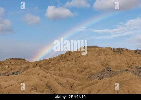 RoadTrip in inverno attraverso il semi-deserto Bardenas Reales, Navarra, Spagna. Riserva della Biosfera UNESCO con, tra gli altri, Castil de Tierra, i Monti Pisquerra e Bardena Blanca. Arcobaleno. Foto Stock