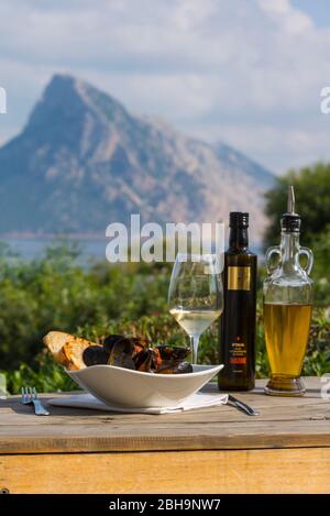 Italia, isola mediterranea Sardegna, spiaggia di Porto Taverna / Spiaggia Porto Taverna, isola Tavolara, ristorante la Tavernetta, terrazza, Zuppa di Cozze, vongole, vino e olio d'oliva Foto Stock