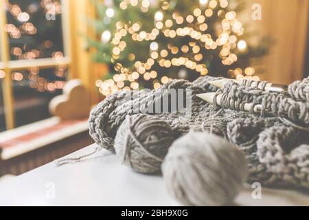 Gemütliches Weihnachten mit schöner Beleuchtung und dem Strickzeug mit großen Nadeln und schöner Wolle. Foto Stock