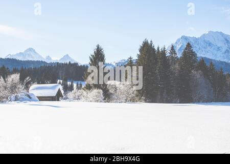 Una capanna innevata a Tennsee vicino a Krün in inverno con vista sul massiccio del Wetterstein e sulle cime delle Alpi a Landkreis Garmisch-Partenkirchen, Baviera, Germania. Foto Stock