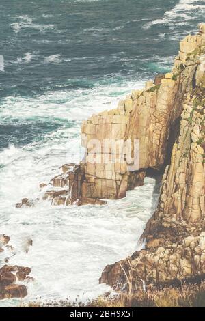 Wellen und Gischt am Fels, an der Küste bei Lands End, Penzance, Cornovaglia, Inghilterra, Großbritannien Foto Stock