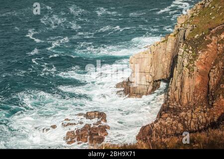 Wellen und Gischt am Fels, an der Küste bei Lands End, Penzance, Cornovaglia, Inghilterra, Großbritannien Foto Stock
