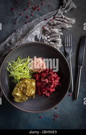 Catrame di manzo con mirtilli rossi secchi e daikon su sfondo grigio. Cucchiaio, forchetta e tovaglia grigia Foto Stock