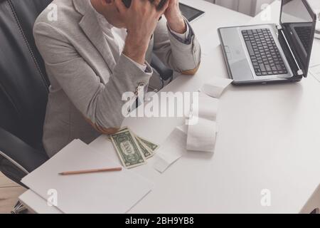 Il giovane uomo frustrato a casa sua per debito. Foto Stock