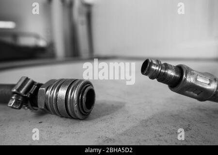 un tubo flessibile dell'aria compressa con giunto è situato sul pavimento di un'officina Foto Stock