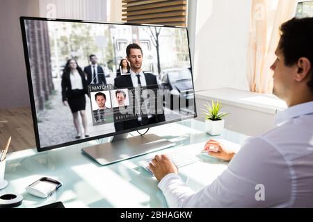 Operatore CCTV che guarda le riprese di sorveglianza utilizzando il riconoscimento facciale ai Foto Stock