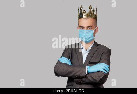 Giovane uomo d'affari in corona e maschera facciale protettiva e guanti. Rimani a casa durante la quarantena del coronavirus Covid-19. Spazio vuoto per il testo. Foto Stock