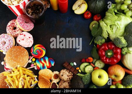 cibo sano o non sano. Foto di concetto di cibo sano e malsano. Frutta e verdura contro ciambelle, dolci e hamburger a tavola Foto Stock