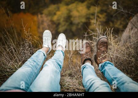 Uomo e donna riposano su Cliff Edge con le gambe appese Foto Stock