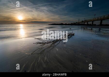 Ostsee im strahlenden Gegenlicht mit der Seebrücke in Wustrow und Spiegelung der schönen Wolken am Strand Foto Stock