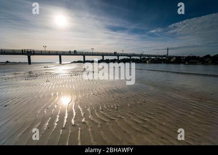 Ostsee im strahlenden Gegenlicht mit der Seebrücke in Wustrow und Spiegelung der schönen Wolken am Strand Foto Stock