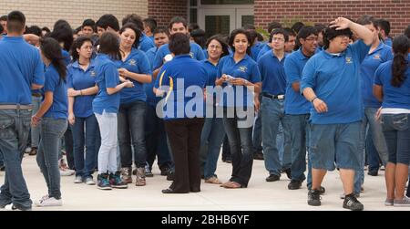 Pharr Texas USA, 13 2010 maggio: Gli studenti delle scuole superiori della Pharr-San Juan-Alamo School District's Early College High School T-STEM Academy mescolano all'esterno mentre aspettano i loro bus scolastici presso il campus nel Texas estremo sud. Gli studenti devono indossare le magliette blu uniformi durante la giornata scolastica. La scuola offre agli studenti la possibilità di guadagnare crediti universitari mentre si seguono corsi avanzati di scuola superiore e ottenere un inizio di testa sul college. ©Bob Daemmrich Foto Stock