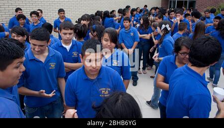 Pharr Texas USA, 13 2010 maggio: Gli studenti delle scuole superiori della Pharr-San Juan-Alamo School District's Early College High School T-STEM Academy mescolano all'esterno mentre aspettano i loro bus scolastici presso il campus nel Texas estremo sud. Gli studenti devono indossare le magliette blu uniformi durante la giornata scolastica. La scuola offre agli studenti la possibilità di guadagnare crediti universitari mentre si seguono corsi avanzati di scuola superiore e ottenere un inizio di testa sul college. ©Bob Daemmrich Foto Stock