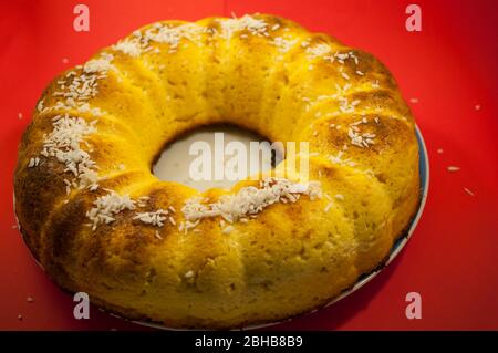 Cheesecake fatto in casa con un viso sorridente che serve su piatto su sfondo rosso (messa a fuoco selettiva; primo piano) Foto Stock