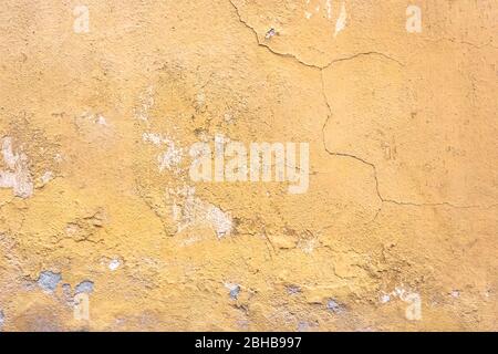 Grunge parete intonaco con sfondo giallo graffiato. Vecchio muro con buccia color palude stucco texture. Carta da parati vintage. Decadimento e crepe. Abstra ruvida Foto Stock