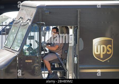 Los Angeles, CA / USA - 24 aprile 2020: Un autista per l'UPS United Parcel Service indossa una maschera con il logo dell'azienda mentre parcheggia un camion di consegna durante la Foto Stock