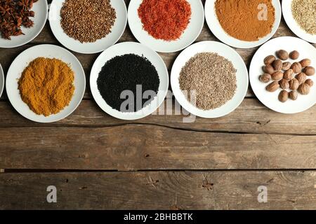 Spezie diverse su piatti, su vecchio tavolo di legno Foto Stock