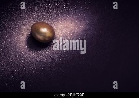 Uovo d'oro e vernice spray Galaxy su sfondo viola. Cosmo astratto. Felice pasqua concetto. Foto Stock