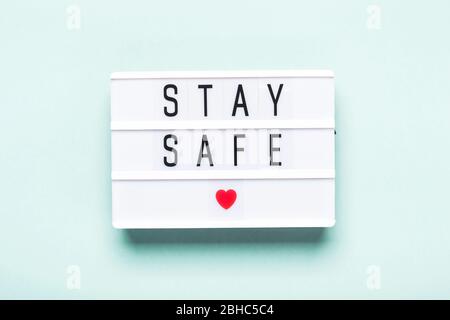 Rimani a casa, sicurezza. RESTA AL RISPARMIO scritto su lavagna luminosa su sfondo blu. Autoisolamento e quarantena durante la pandemia di coronavirus Covid-19. Foto Stock