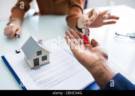 Il realtor che fornisce le chiavi della casa al cliente dopo la firma del contratto Foto Stock