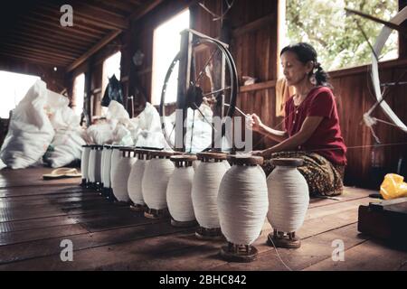 Inle, Myanmar. 30 luglio 2019: Donna che lavora a mano. Telaio di loto, seta e cotone all'interno di una struttura per la produzione tessile indigena. Foto Stock