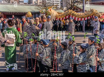 tokyo, giappone - marzo 18 2020: Bambini giapponesi che camminano in fila tenendo un tradizionale shakujou rod ornato con suzu campana durante il tradizionale oro Foto Stock