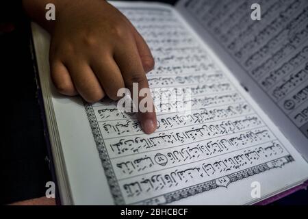 Makassar, Sulawesi del Sud, Indonesia. 25 Aprile 2020. Un ragazzo sta leggendo il Corano seriamente nella sua stanza durante Ramadan mentre aspetta il Breaking the Fast a Makassar, nella provincia di Sulawesi del Sud, Indonesia. Nel mese del Ramadan, ogni musulmano effettua il digiuno ed anche l'altro culto come la lettura del Corano e fare il dhikr per riempire il tempo libero, particolarmente durante l'epidemia di Covid-19. Credit: Herwin Bahar/ZUMA Wire/Alamy Live News Foto Stock