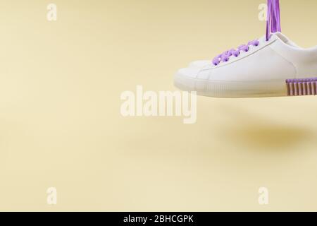 Sneaker bianche con lacci viola su sfondo beige Foto Stock