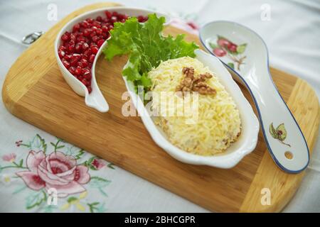 Insalata tradizionale russa Mimoza. Isolato su sfondo di legno. Vista dall'alto. INSALATA DI POLLO con noci e funghi . Melograno granulato Foto Stock