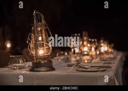 Le lanterne kerosene forniscono un'atmosfera classica safari ad un tavolo da pranzo all'aperto, Chikwenya, concessione safari, Parco Nazionale piscine Mana, Mashonaland We Foto Stock
