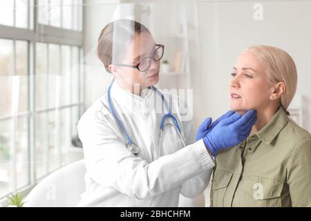 Medico che esamina la donna anziana con problema della ghiandola tiroidea in clinica Foto Stock