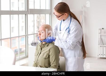 Medico che esamina la donna anziana con problema della ghiandola tiroidea in clinica Foto Stock