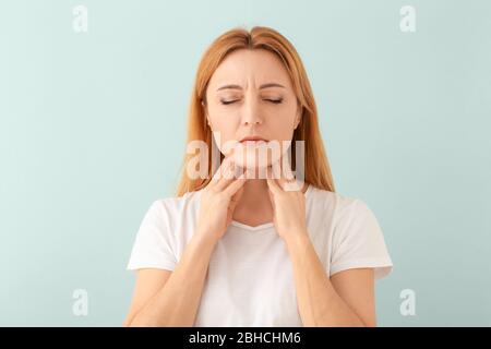 Donna con problema della ghiandola tiroidea su sfondo chiaro Foto Stock