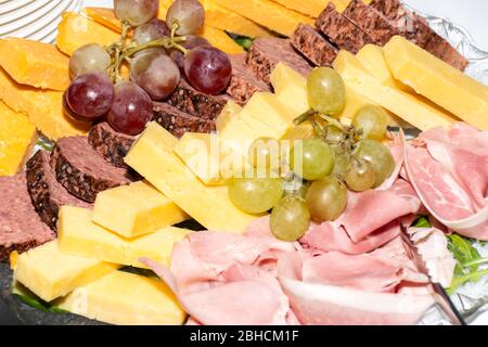 Selezione di antipasti di affettati freschi: Prosciutto, formaggio, pomodori secchi e antipasti di carne al vino serviti su un piatto di vetro durante il brunch, la colazione, il banchetto o Foto Stock