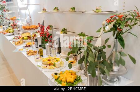 Gustosi piatti di tartine in linea appesi con antipasti di caviale e formaggio cremoso, isolati su sfondo bianco, spuntini finger food durante il brunch dell'hotel Foto Stock