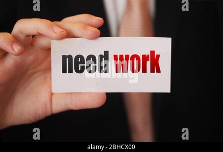 Testo di lavoro di bisogno su carta businessman tiene. Concetto di crisi globale della forza lavoro qualificata e disoccupata Foto Stock