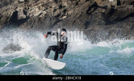 Un'immagine panoramica di un surfista maschile maturo che cavalca un'onda a Fistral a Newquay in Cornovaglia. Foto Stock