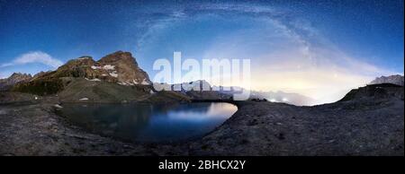 Vista panoramica del picco piramidale Cervino che riflette sul foglio di acqua cristallina sotto il cielo notturno con le stelle. Bellissima strada Lattea su montagne rocciose e piccolo lago. Concetto di natura, notte. Foto Stock