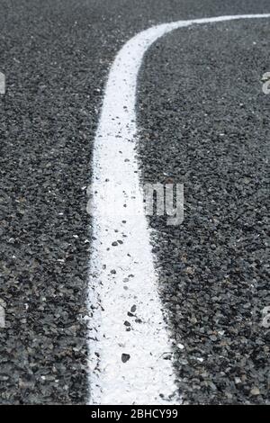 Segnaletica stradale verticale bianca al centro dell'immagine che scorre verso il basso e si incurva verso l'alto Foto Stock