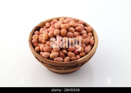 Arachidi o arachis crudi in una ciotola di legno su sfondo bianco Foto Stock