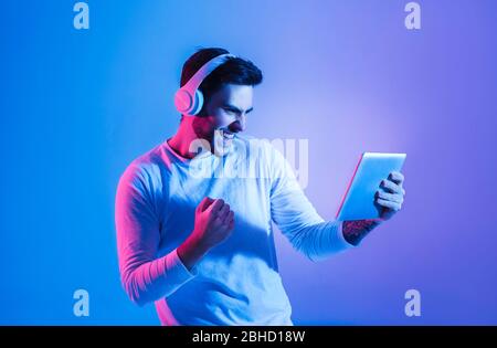 Guy si rallegra per aver vinto il gioco online su tablet Foto Stock