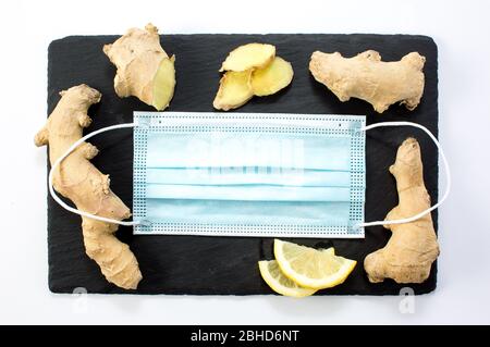 Limone, zenzero, miele, maschera medica per misure preventive su sfondo blu. Rimani in salute. Messa a fuoco selezionata Foto Stock