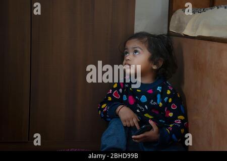 indiano infelice bambino seduto in angolo con il cellulare Foto Stock