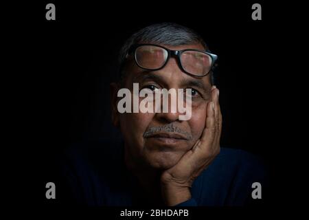 Primo piano ritratto di pensiero senior uomo su sfondo nero Foto Stock