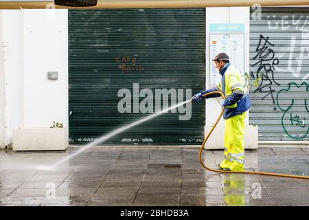 GRANADA, SPAGNA, 23 APRILE 2020 operaio di manichette che acque la strada della città Foto Stock