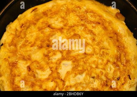 Gustosa tortilla spagnola in una padella. Particolare di un'omelette con uova, patate e cipolle. Foto Stock