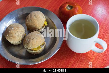 una semplice colazione salutare con tre panini di grano con uova a curry in un piatto di acciaio inossidabile e un tè alle erbe in foglia di sop acour in una tazza bianca Foto Stock