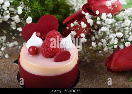 Mini torta alla vaniglia di lamponi dai colori vivaci, festa dell'amore, festa. Dessert di macaroon fresco e lussuoso a forma di cuore. Anniversario di festa mangiare. Madre Foto Stock