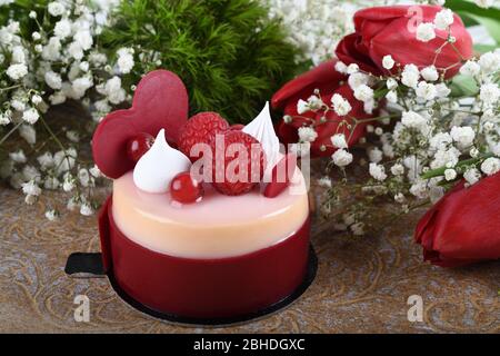 Mini torta alla vaniglia di lamponi dai colori vivaci, festa dell'amore, festa. Dessert di macaroon fresco e lussuoso a forma di cuore. Anniversario di festa mangiare. Madre Foto Stock