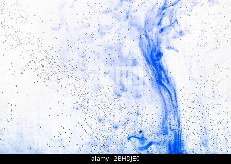 bolle d'aria sulla superficie di vetro della bottiglia piatta e l'inchiostro blu fluiscono nell'acqua sullo sfondo Foto Stock